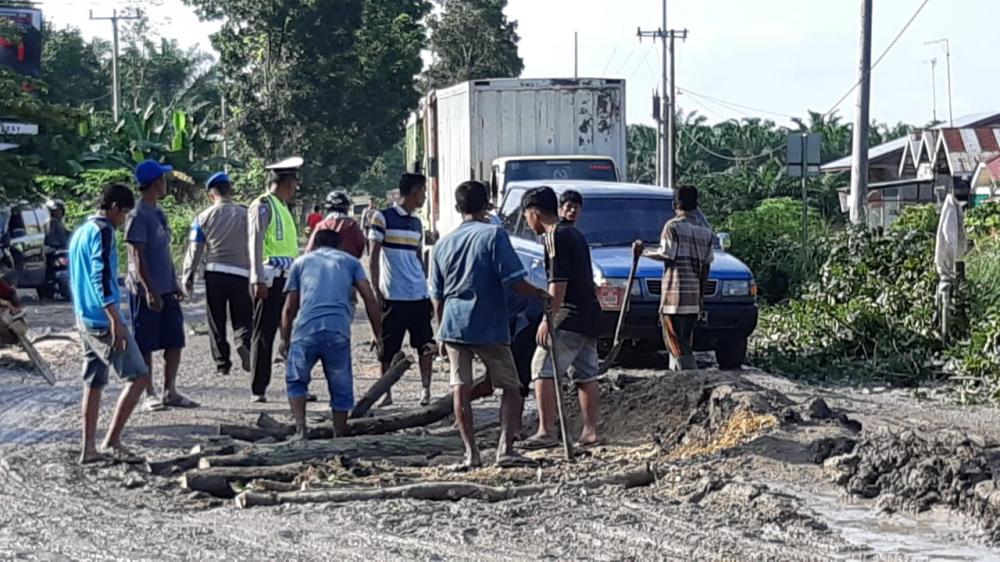 Personel Satlantas Bersama Warga Timbun Jalan Rusak di Petapahan Tapung Mengatasi Macet.